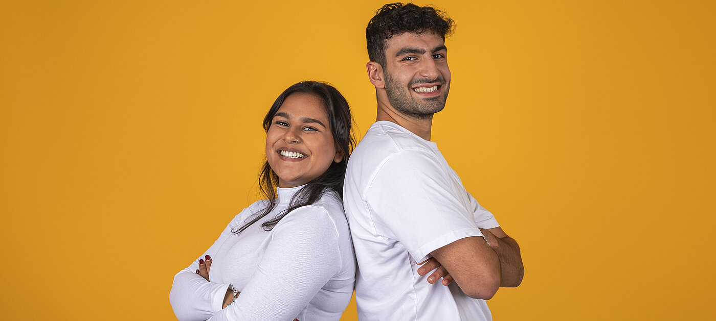 zwei junge Menschen stehen Rücken an Rücken und lächeln